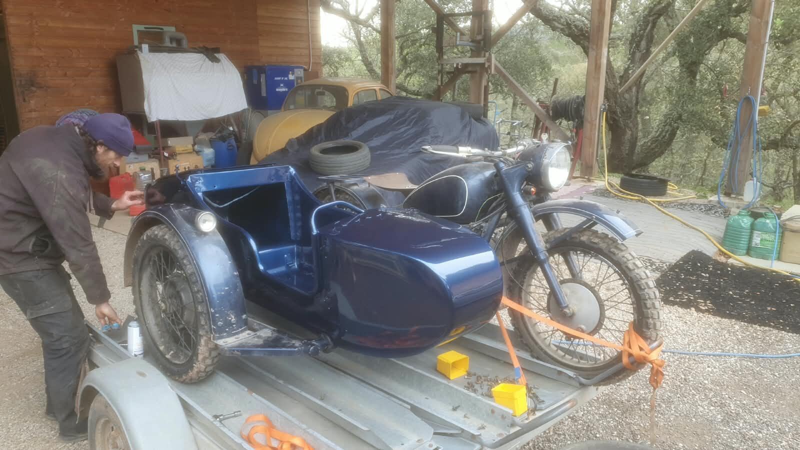 Side-car ancien sanglé sur une remorque devant l’atelier